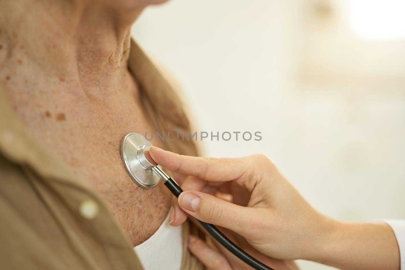 Fragment photo of a medical worker pressing a stethoscope to elderly man chest