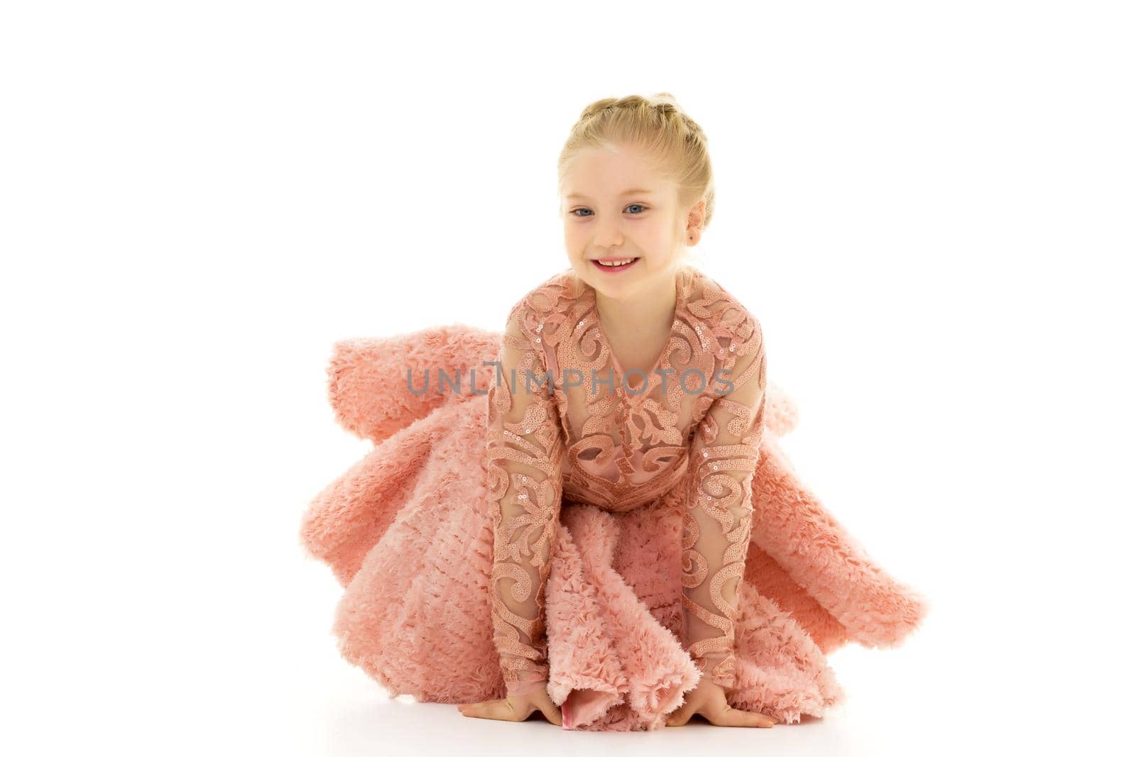 Beautiful little girl kneels in the studio on a white background. The concept of beauty and fashion, children's emotions. Isolated on a white background.