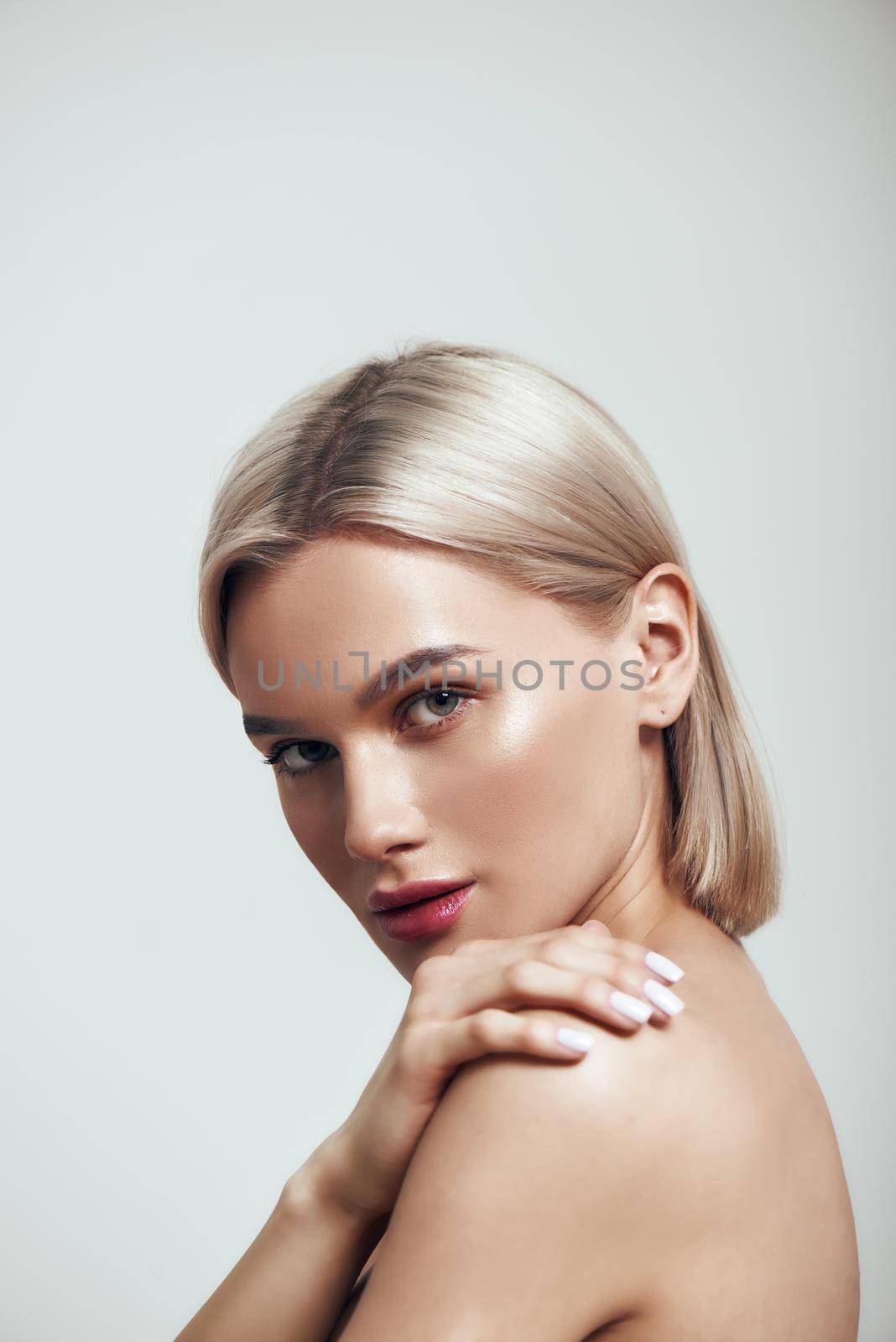 Perfection. Vertical photo of sexy young woman with blond hair and perfect shiny skin looking at camera while standing against grey background by friendsstock