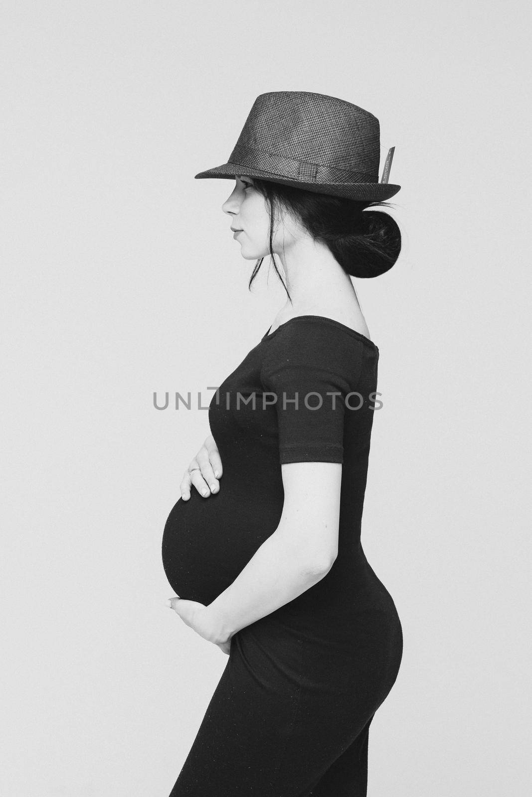 adorable young mum in black dress posing for the camera with her tummy, black and white picture isolated on white background