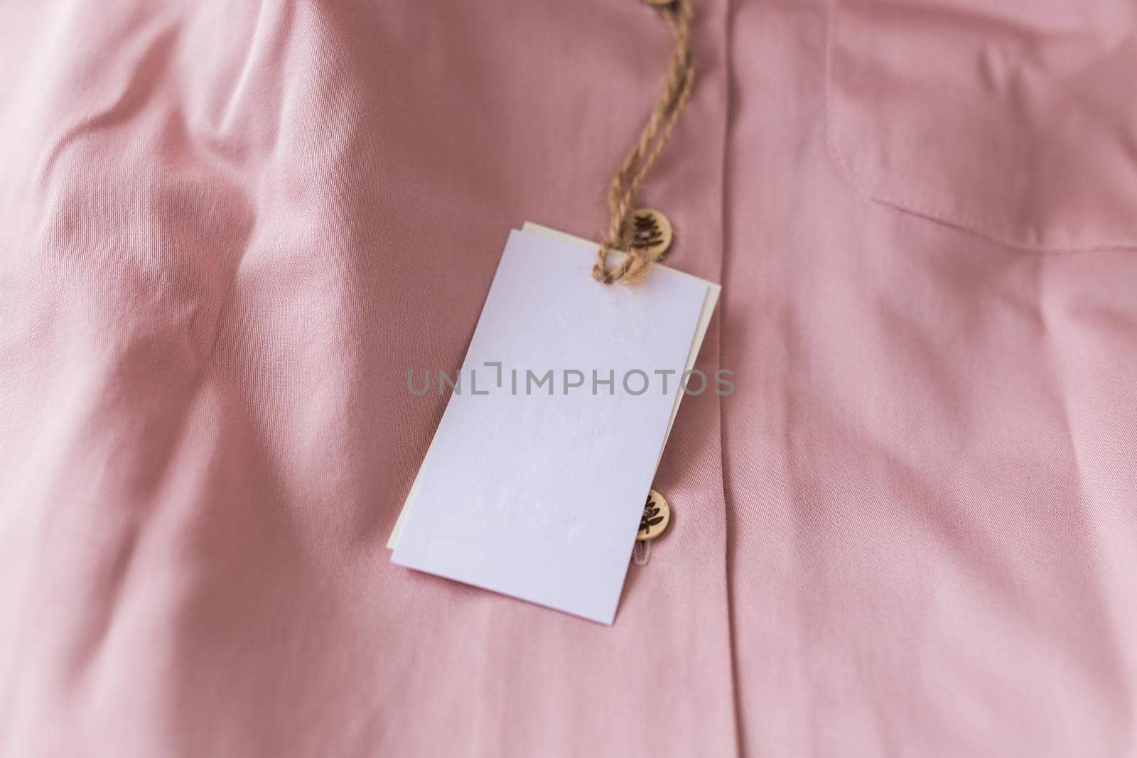 Close-up blank tag label on pink shirt. Copy space