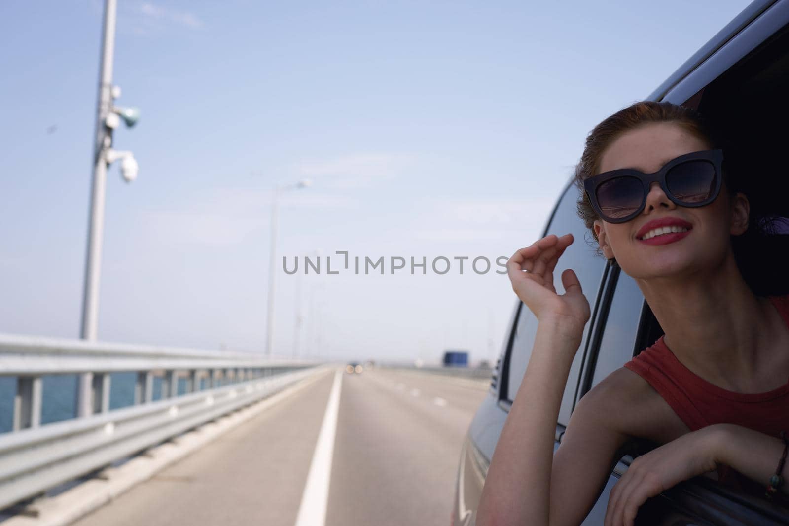 a woman is driving in a car on the road and looking out of the window. High quality photo