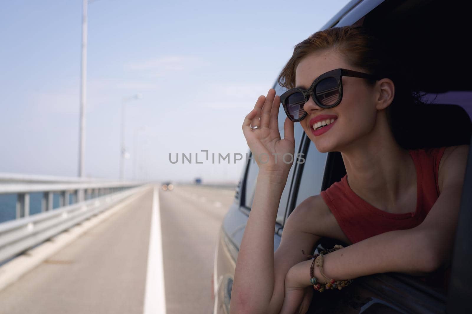 a woman is driving in a car on the road and looking out of the window. High quality photo