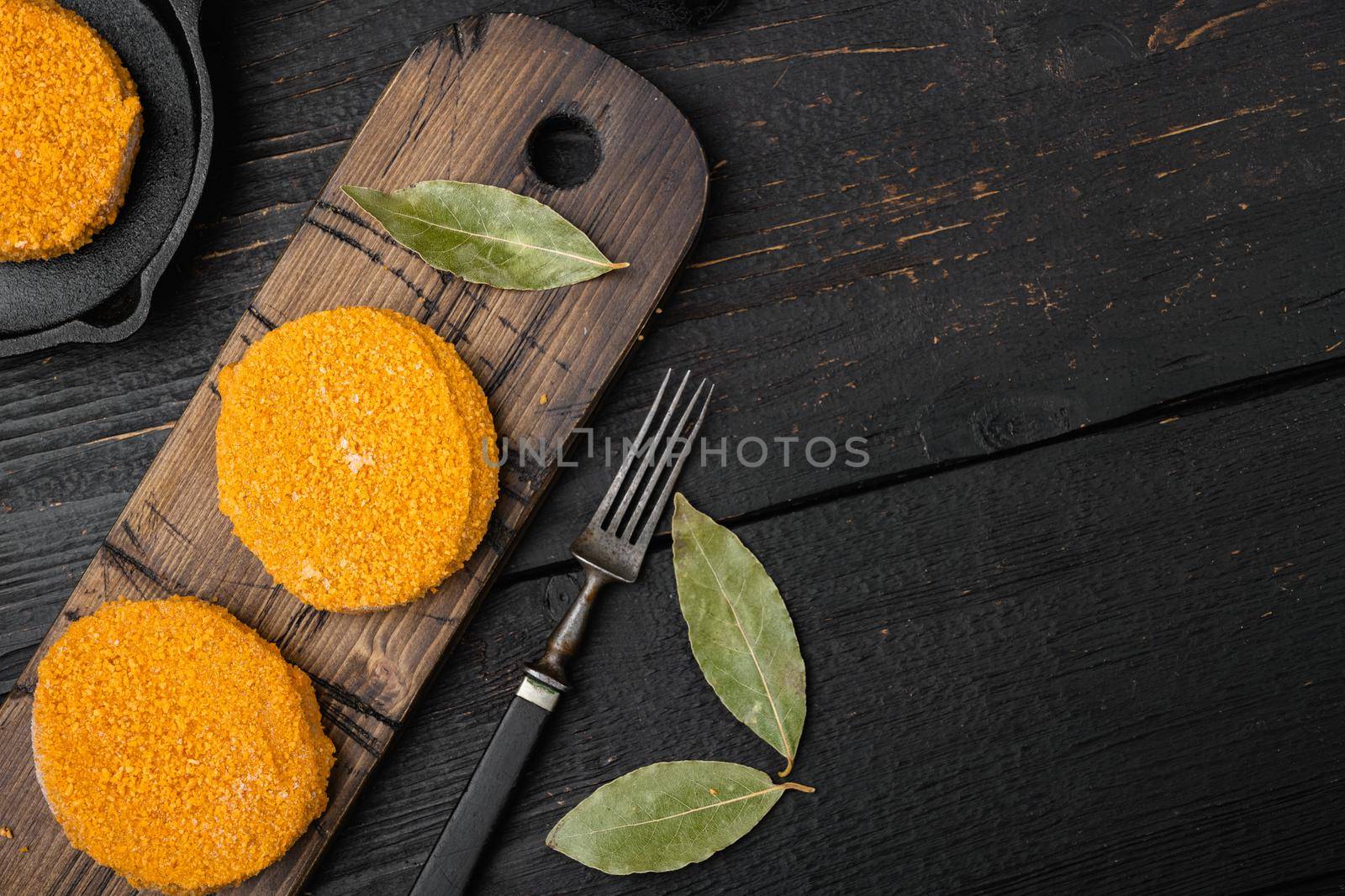Breaded fish patties set, on black wooden table background, top view flat lay, with copy space for text