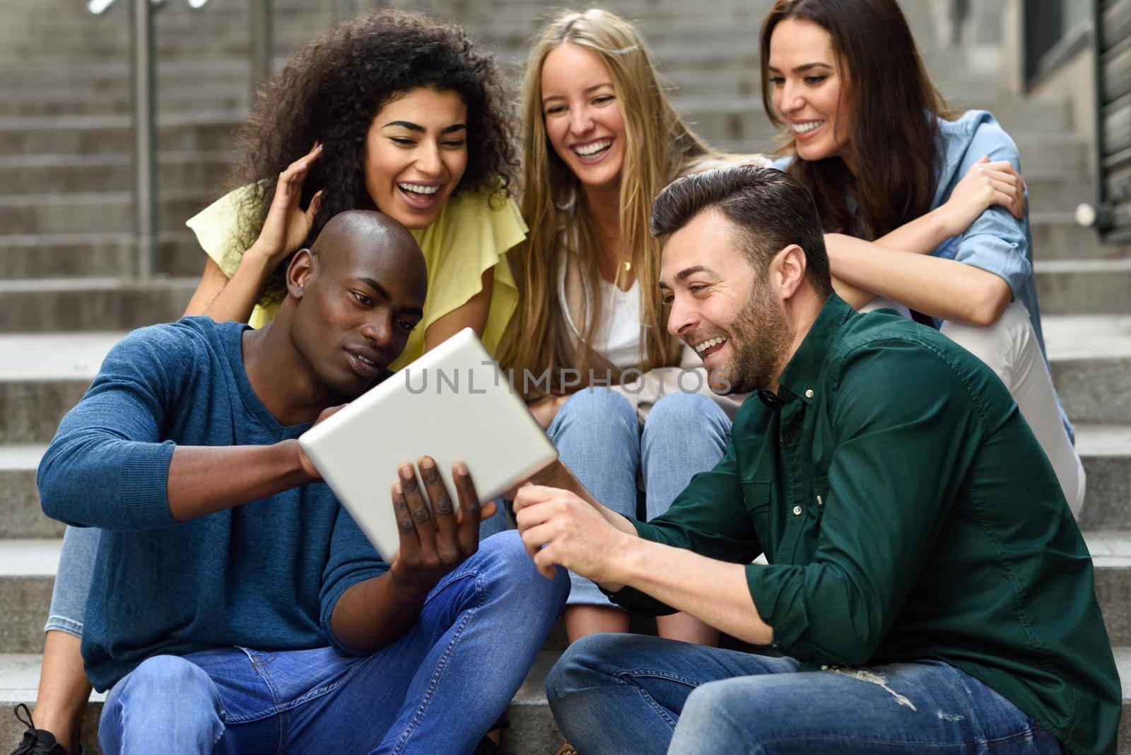 Multi-ethnic group of young people looking at a tablet computer by javiindy