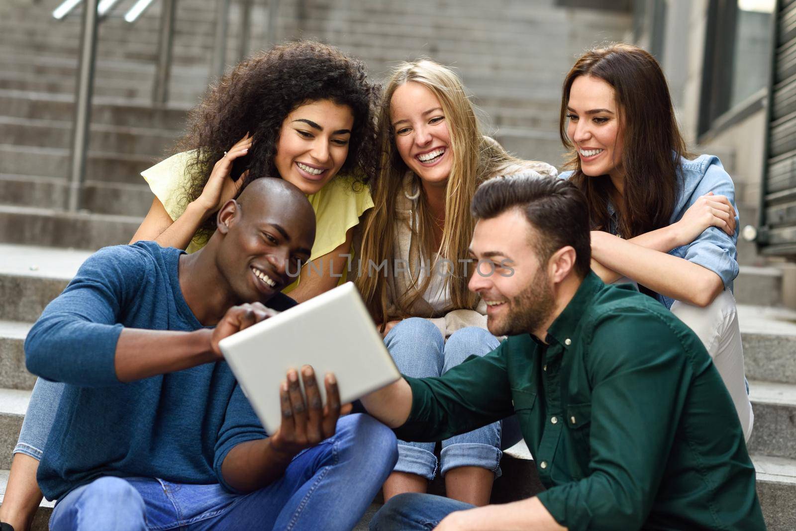 Multi-ethnic group of young people looking at a tablet computer by javiindy