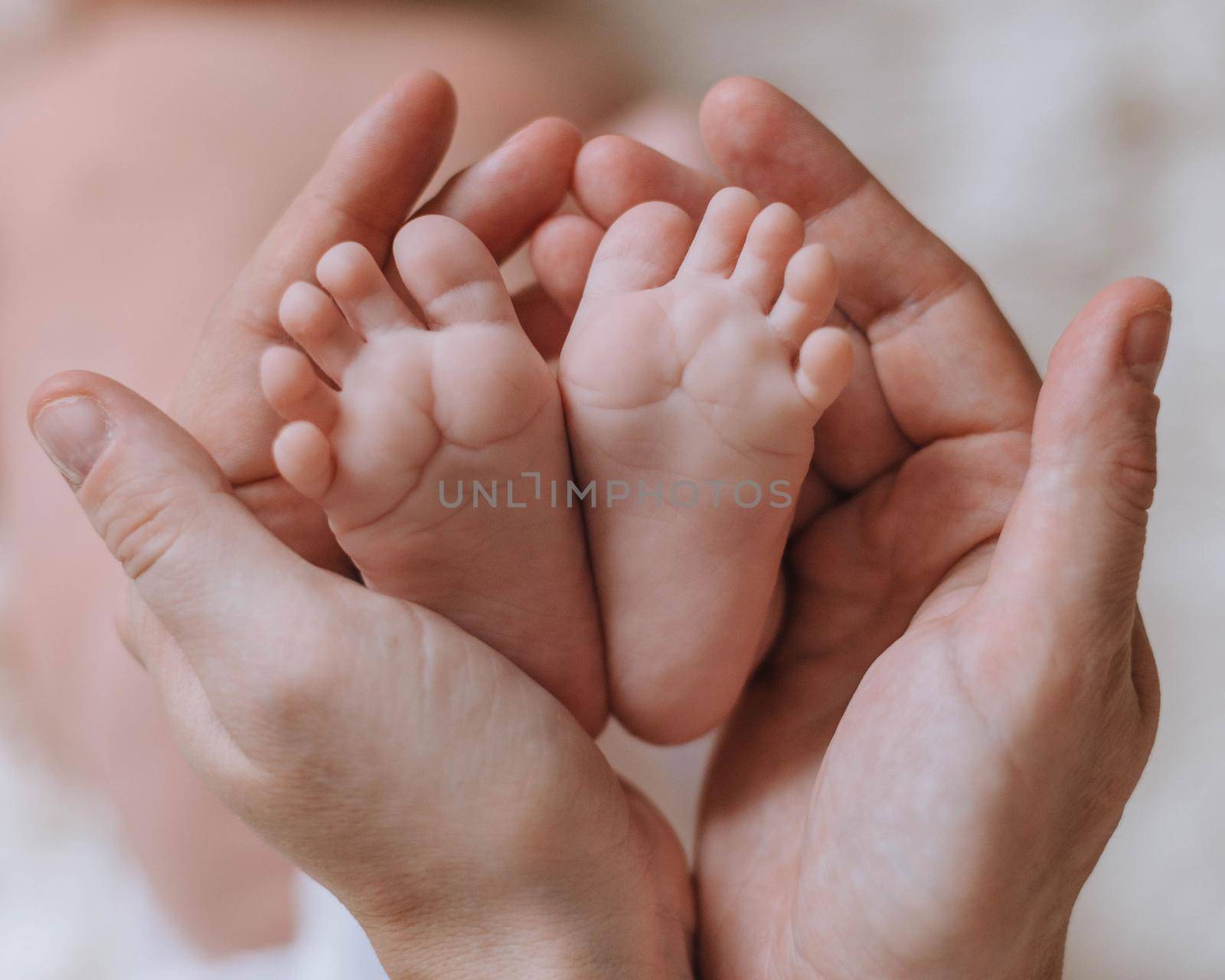 parent is holding little baby feet by Matiunina