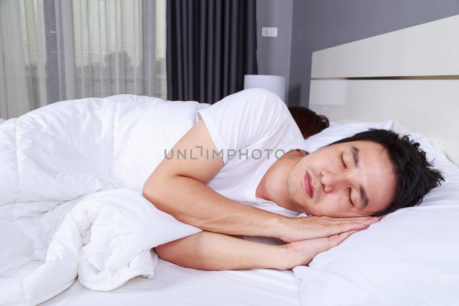 young man sleeping with his wife in a comfortable bed at home