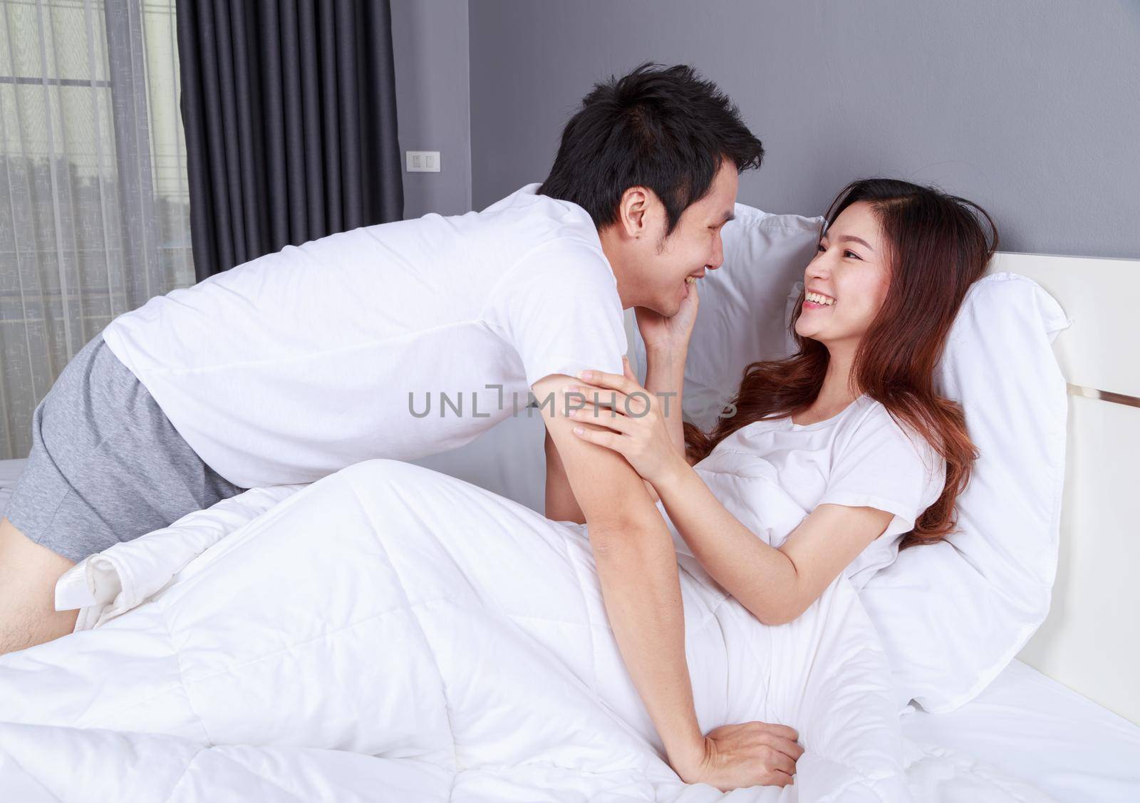 young lovely couple lying in a bed and looking to each other (eyes to eyes)