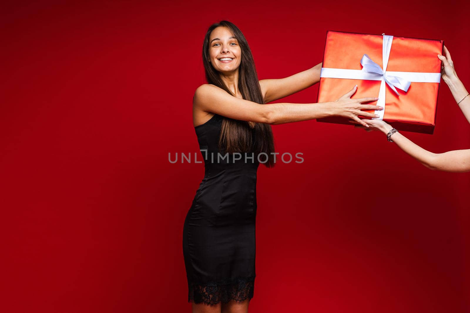 cheerful caucasian woman with attractive appearance with a big box with a present, picture isolated on red background