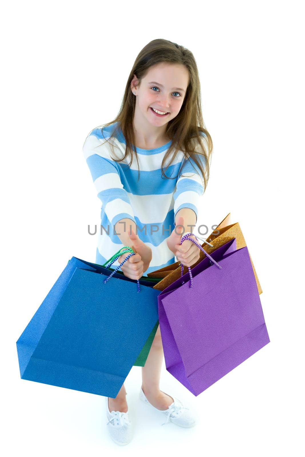 A cheerful little girl is shopping in a store with large, multi-colored paper bags. The concept of holidays, advertising sales. Isolated on white background.