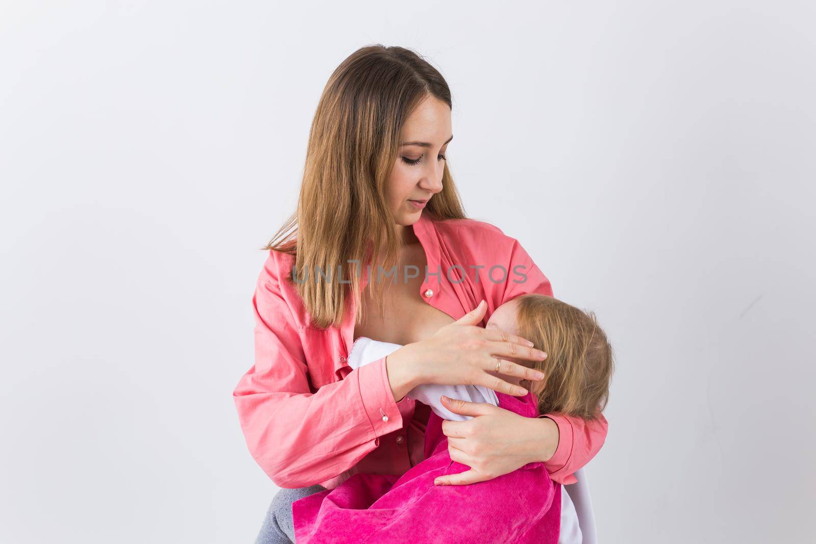 Mother breastfeeding baby in her arms at home. Child eating mother's milk. Young woman nursing and feeding baby. Concept of lactation infant. by Satura86