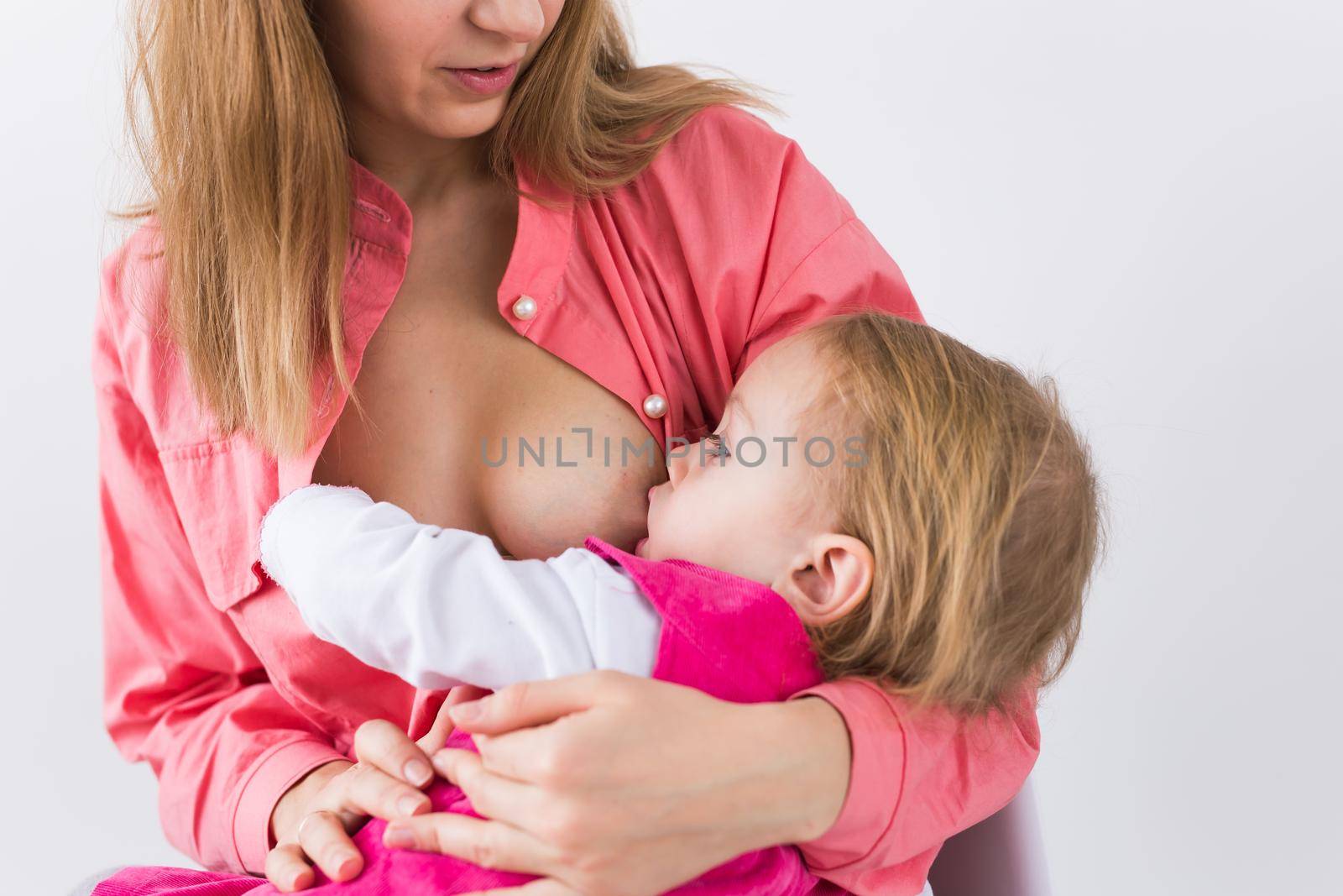 Mother breastfeeding baby in her arms at home. Child eating mother's milk. Young woman nursing and feeding baby. Concept of lactation infant. by Satura86