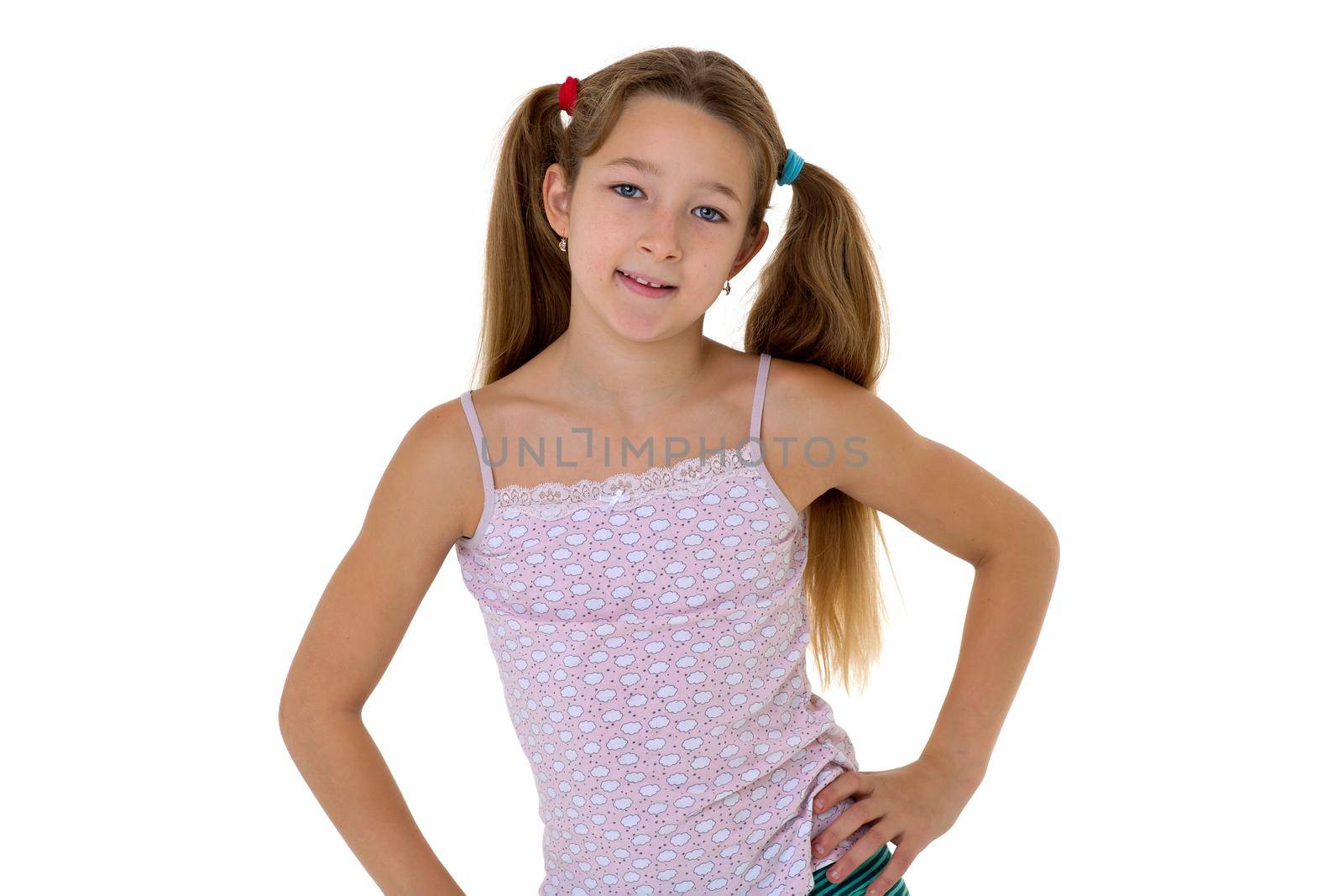 Cute smiling girl standing with hands on her waist. Portrait of preteen child posing in studio against white background.