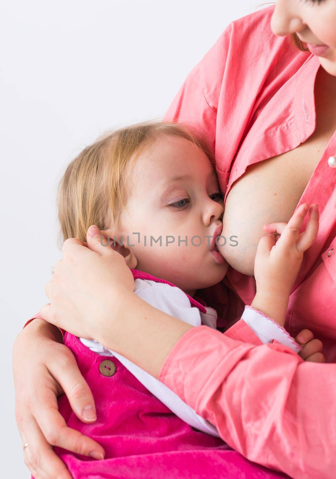 Mother breastfeeding baby in her arms at home. Child eating mother's milk. Young woman nursing and feeding baby. Concept of lactation infant. by Satura86