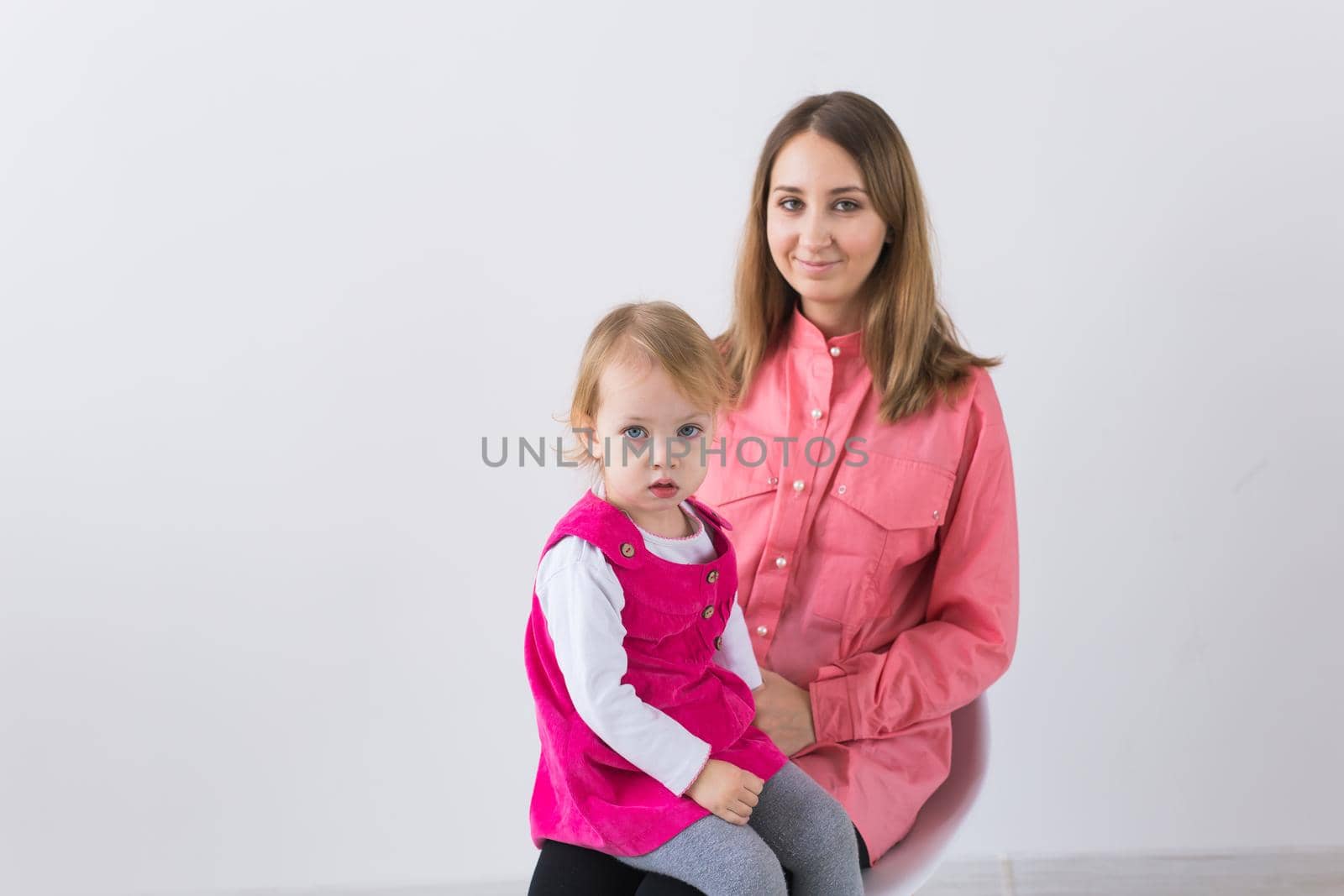 Childhood and family concept - Mother holds baby daughter on white background with copy space.
