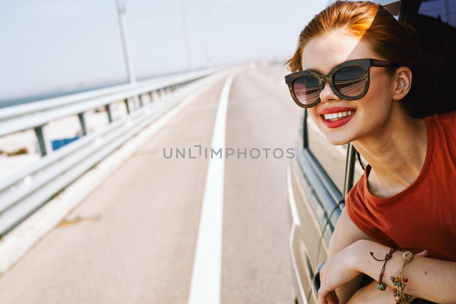 cheerful woman peeking out of the car window trip adventure lifestyle. High quality photo