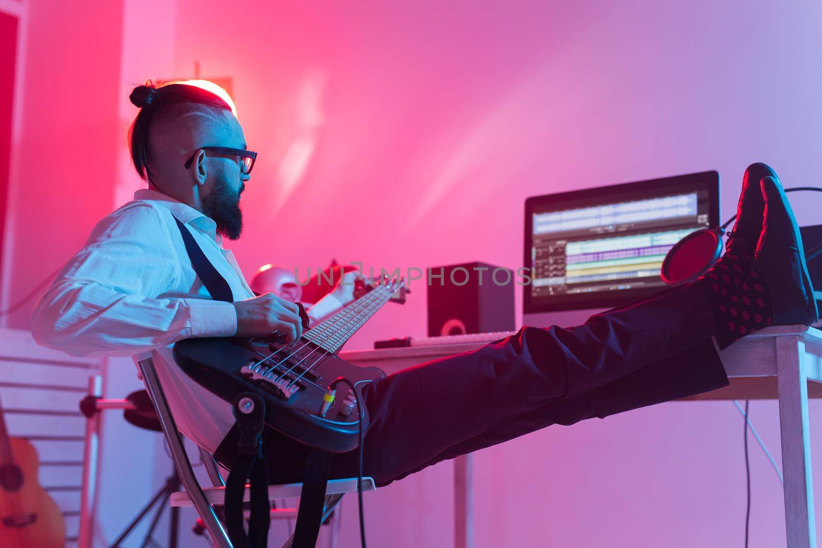 Create music and a recording studio concept - Bearded man guitarist recording electric guitar track in home studio.