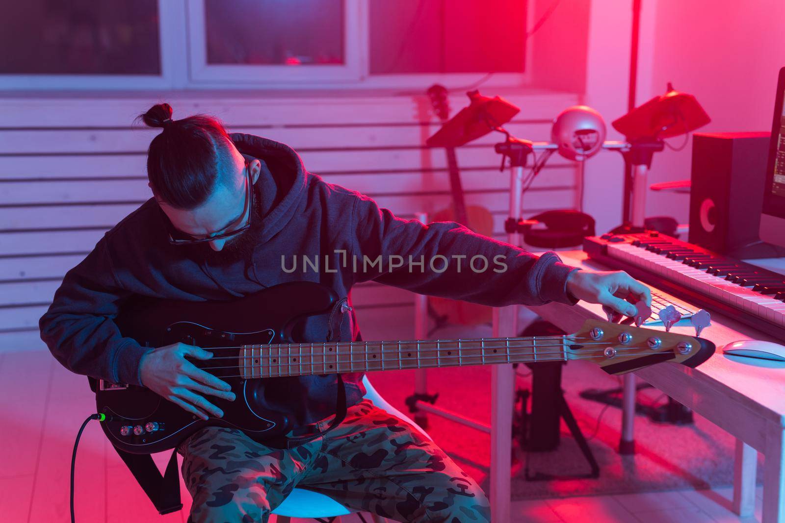 Create music and a recording studio concept - Bearded man guitarist recording electric guitar track in home studio.