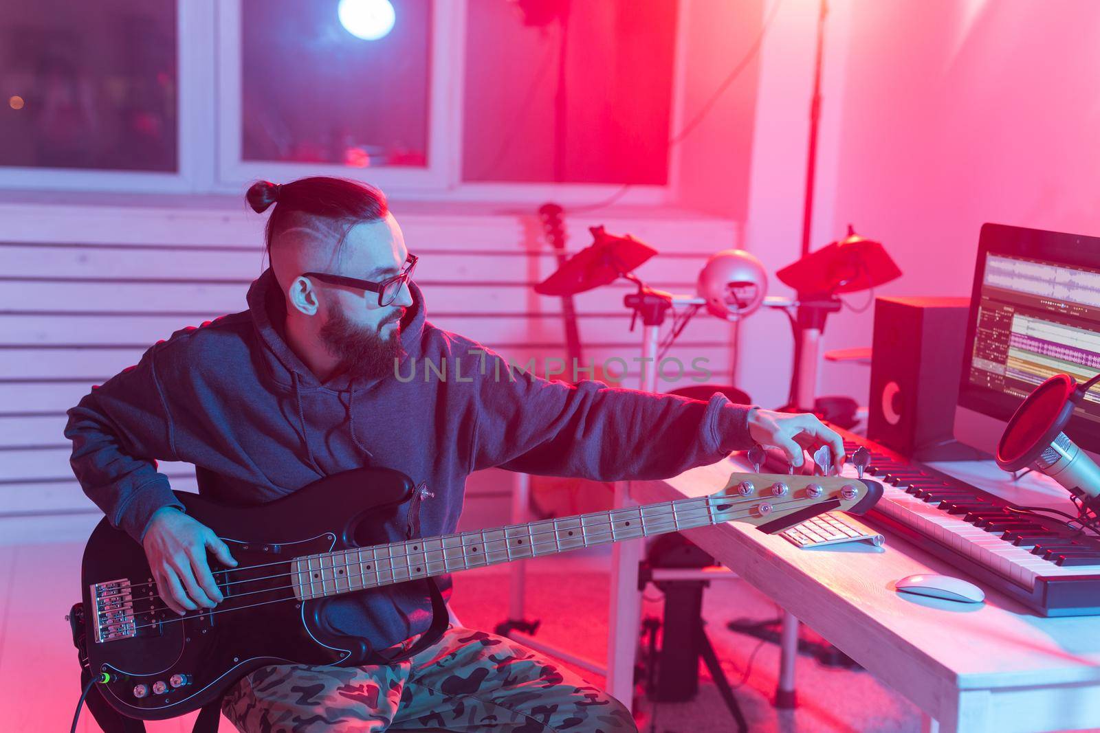 Create music and a recording studio concept - Bearded man guitarist recording electric guitar track in home studio.