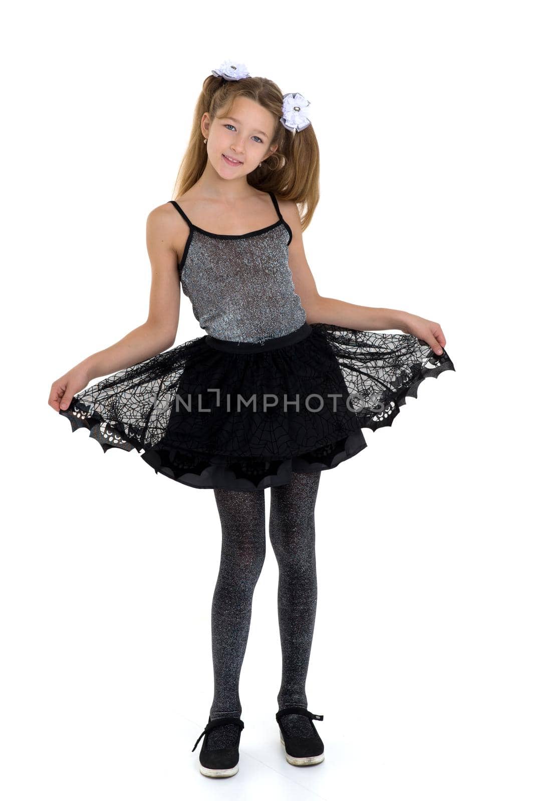 Girl with pigtails in fashionable clothes. Pretty blonde girl in black lace skirt and tank top posing in studio against white background. Full length portrait of preteen child