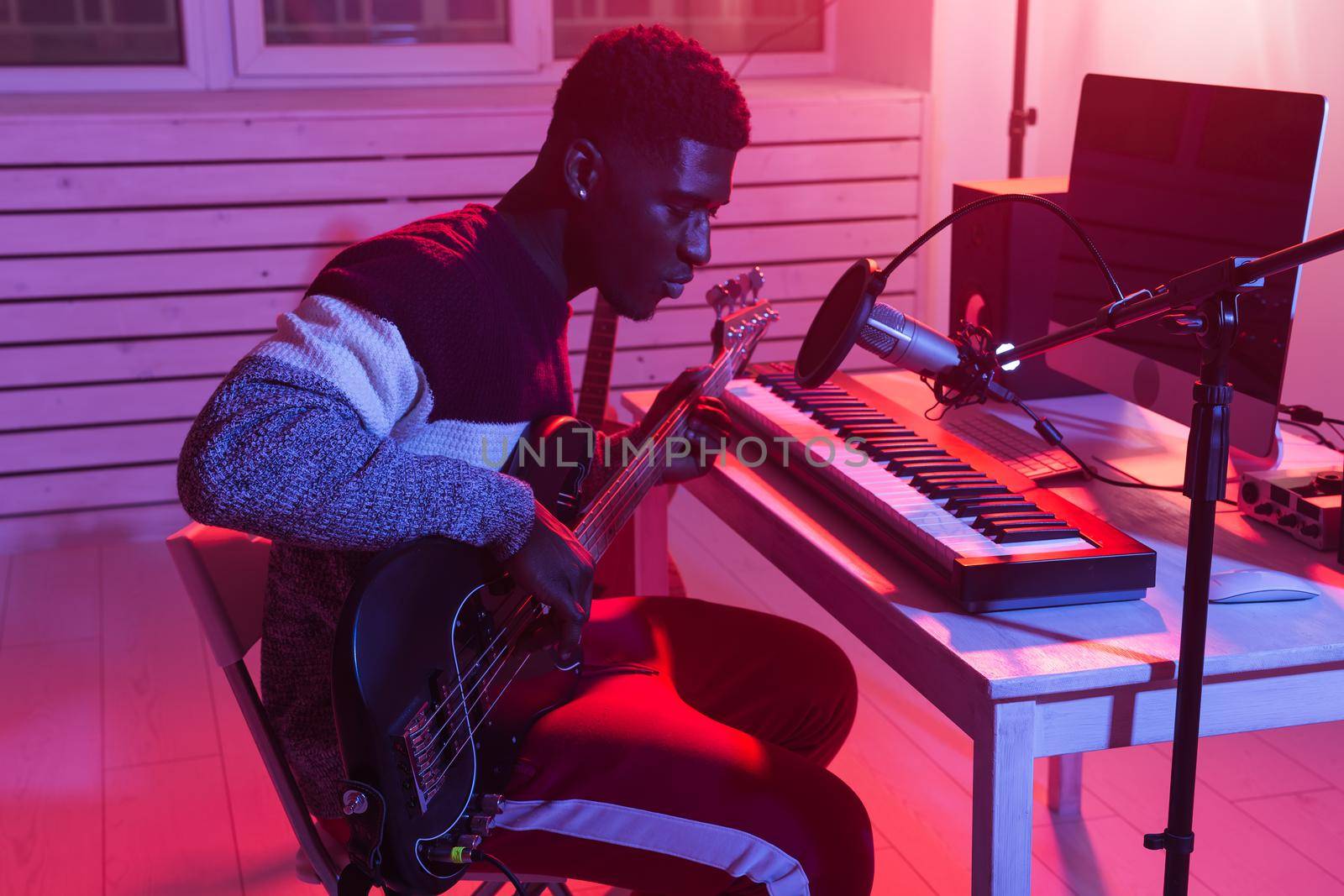 African american professional musician recording guitar in digital studio at home, music production technology concept