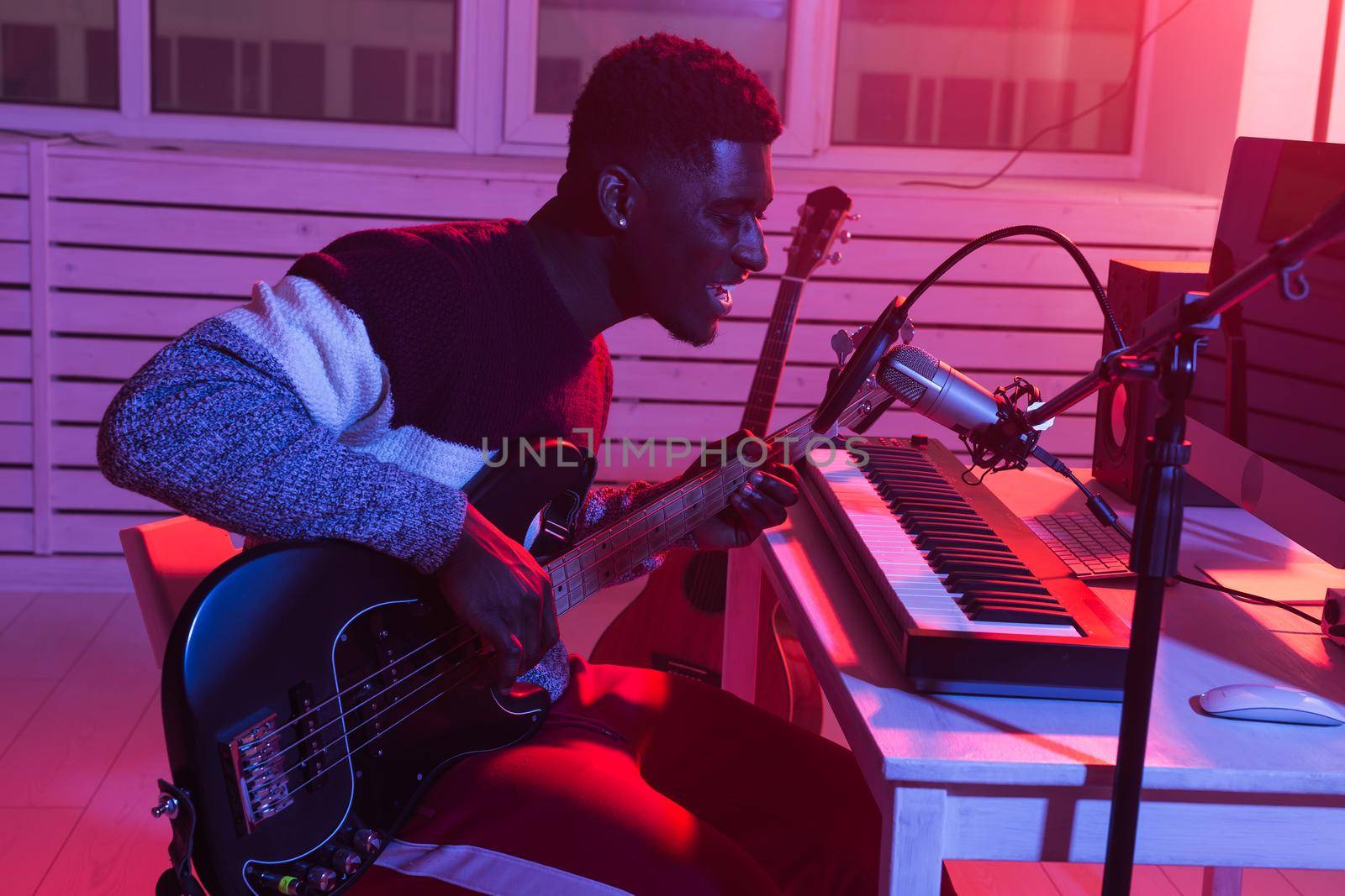 African american professional musician recording guitar in digital studio at home, music production technology concept