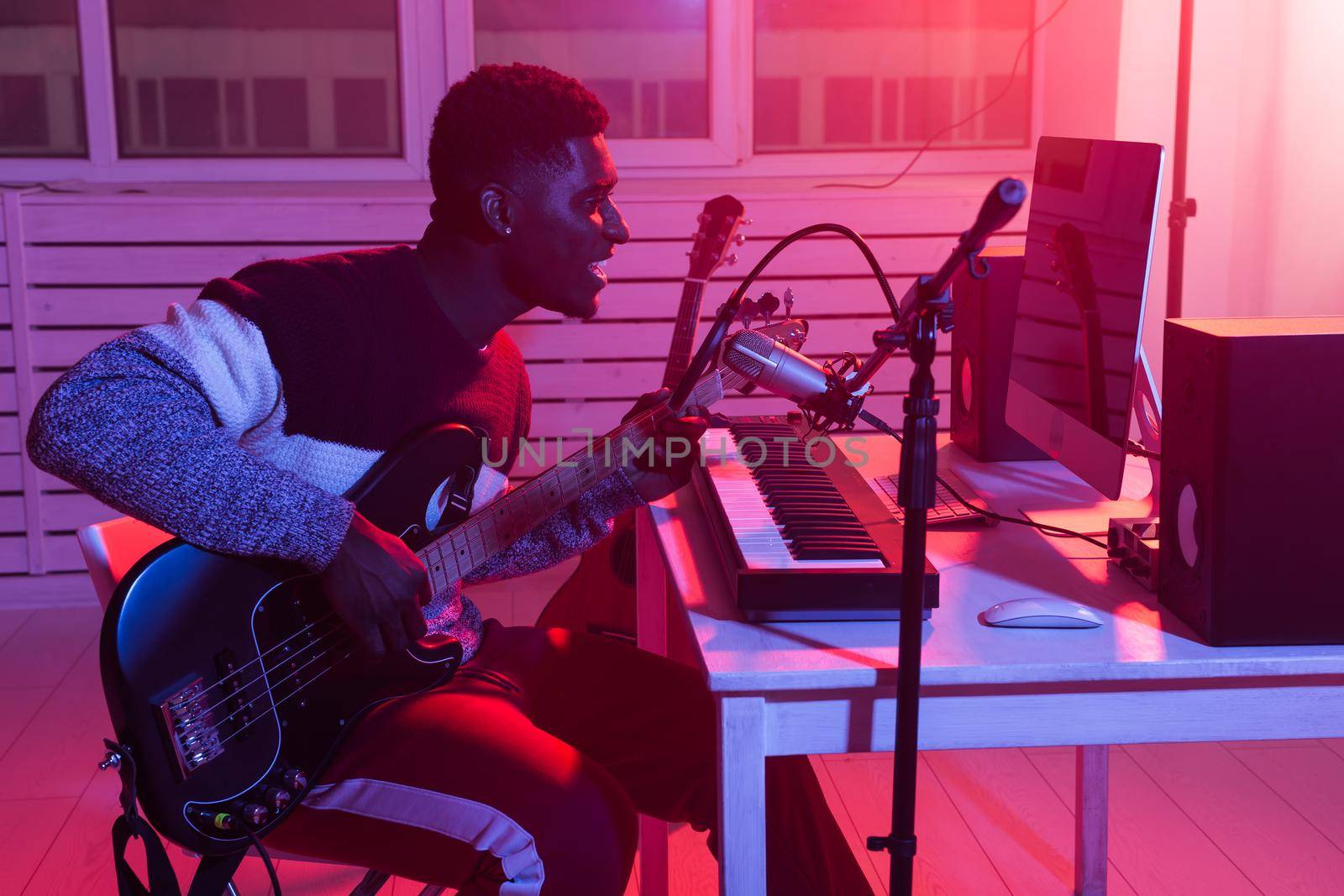 Create music and a recording studio concept - Bearded man guitarist recording electric guitar track in home studio.