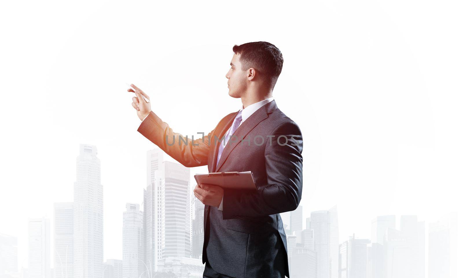 Handsome businessman standing and finger pointing at something. Side view of man in business suit and tie on background foggy cityscape. Financial specialist with raised hand promotion mockup.