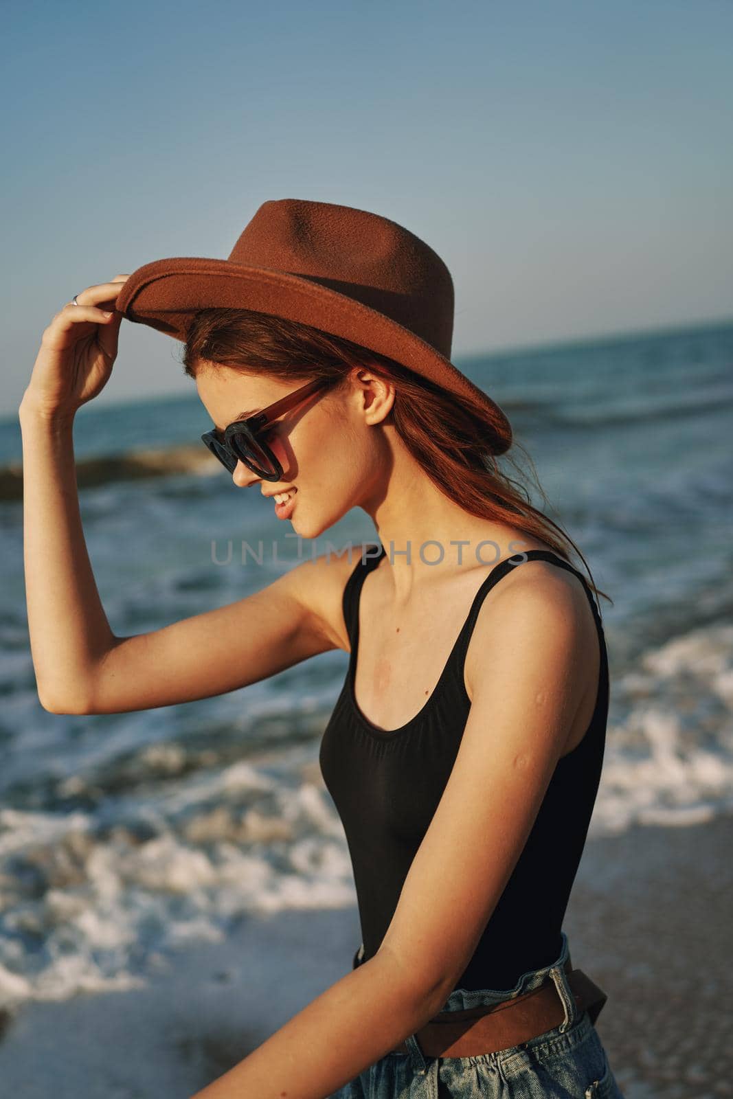 cheerful woman in sunglasses and a hat by the ocean walk summer. High quality photo