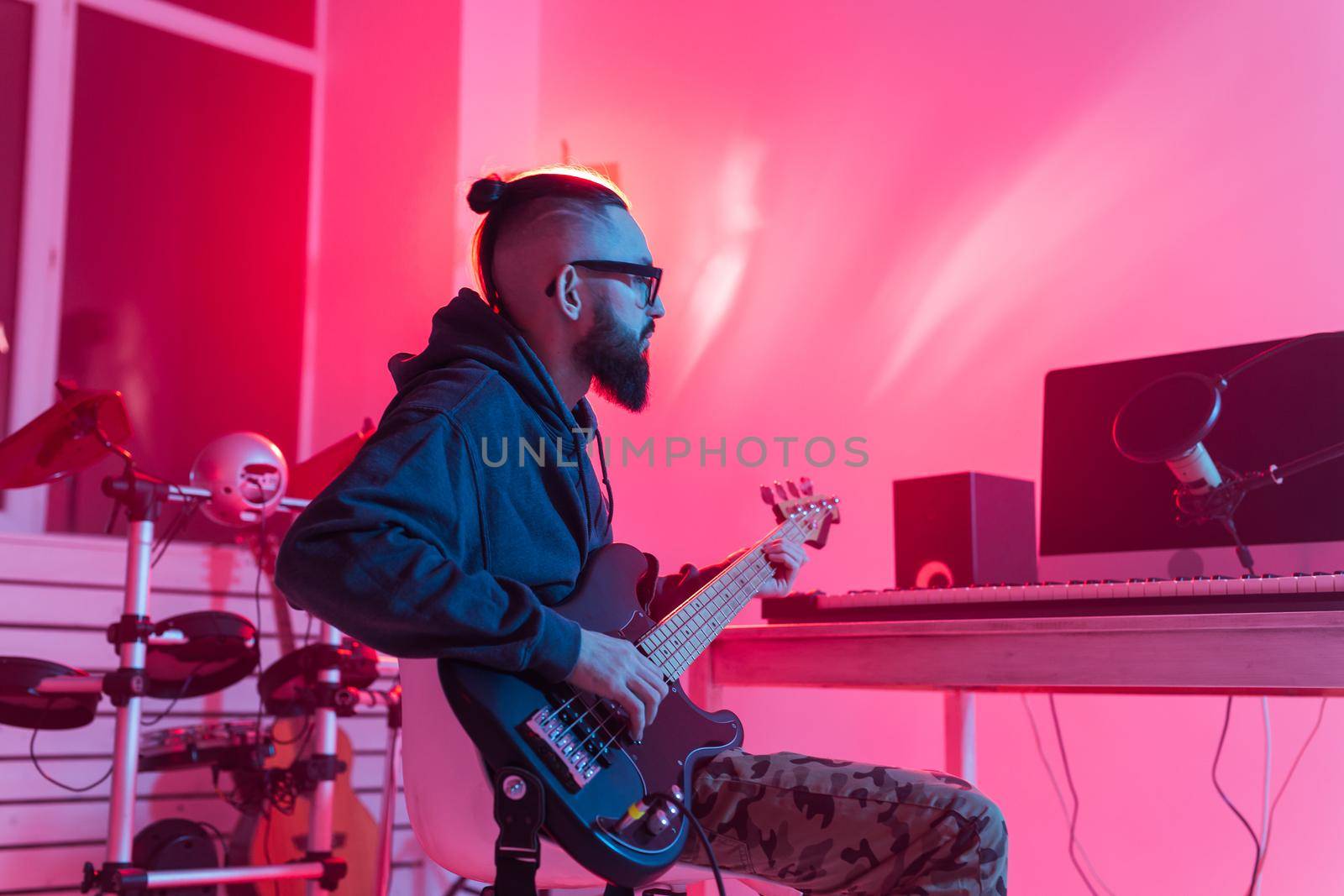 Create music and a recording studio concept - Bearded man guitarist recording electric guitar track in home studio.