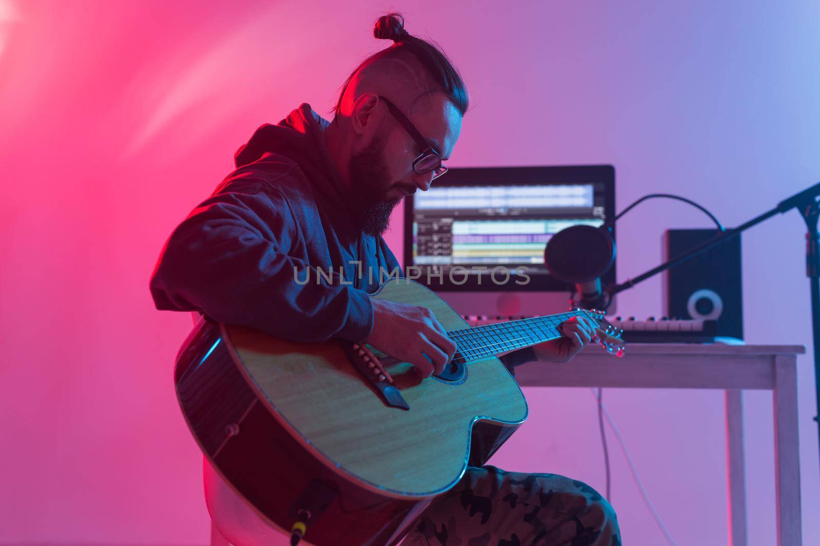 Create music and a recording studio concept - Bearded man guitarist recording electric guitar track in home studio.