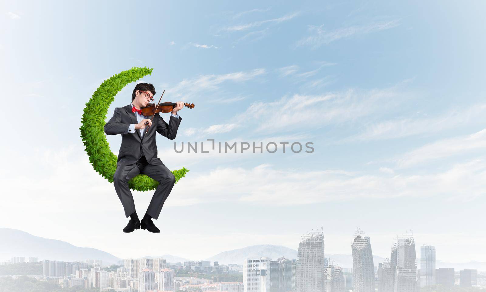 young businessman with a violin. sits on the moon symbol of plants. concept of inspiration in business
