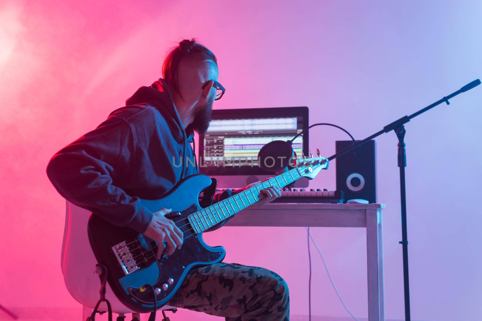 Create music and a recording studio concept - Bearded man guitarist recording electric guitar track in home studio.