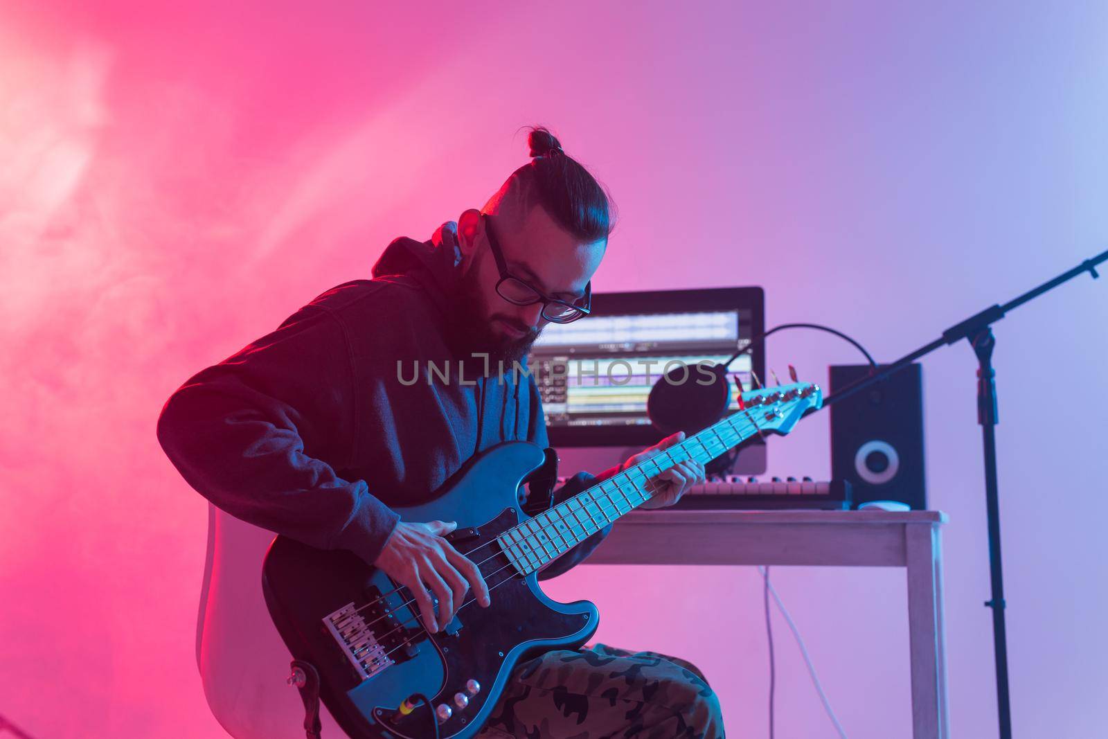 Create music and a recording studio concept - Bearded man guitarist recording electric guitar track in home studio.
