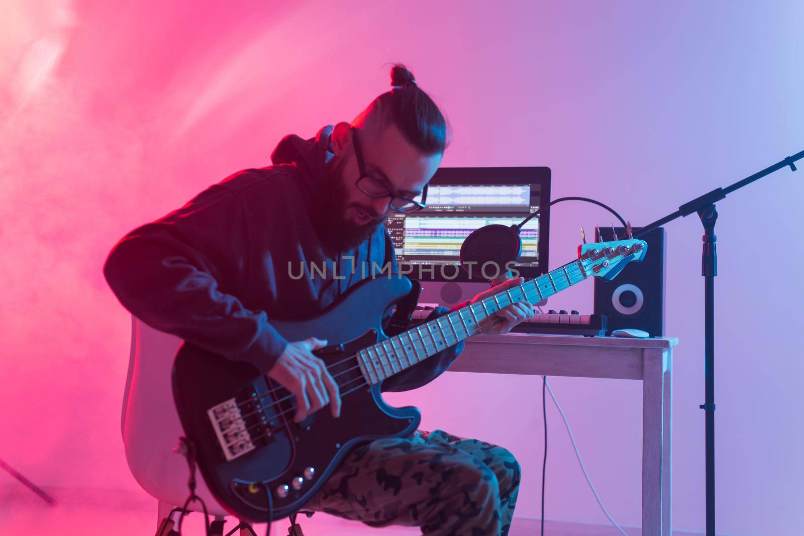 Create music and a recording studio concept - Bearded man guitarist recording electric guitar track in home studio.