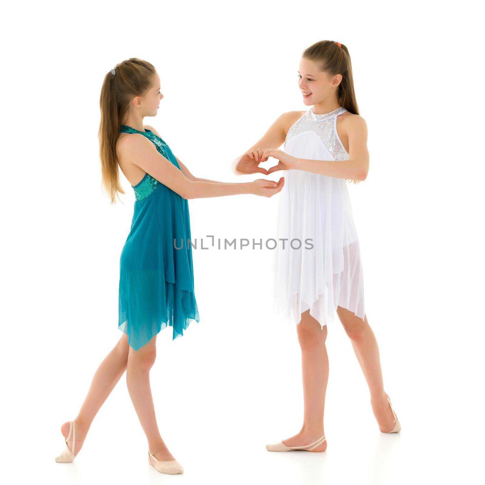 Two adorable girls gymnasts folded hands in the form of a heart. Sign of love. Isolated on a white background.