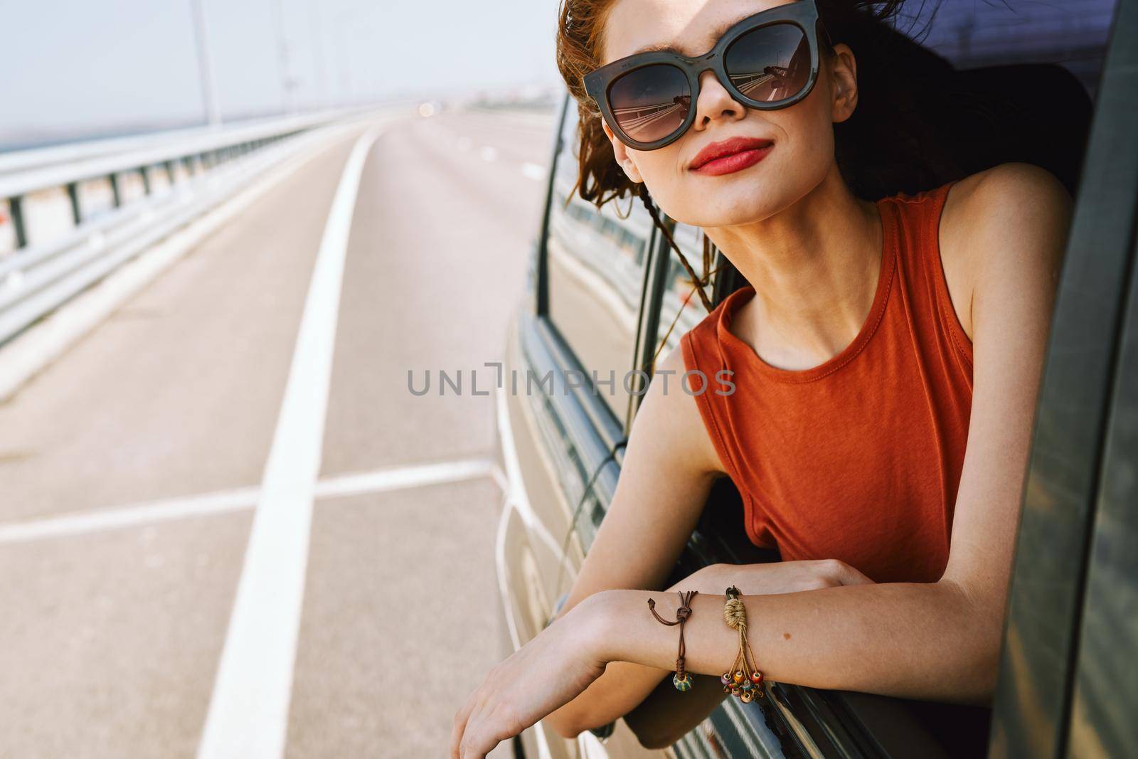 cheerful woman peeking out of the car window trip adventure lifestyle. High quality photo
