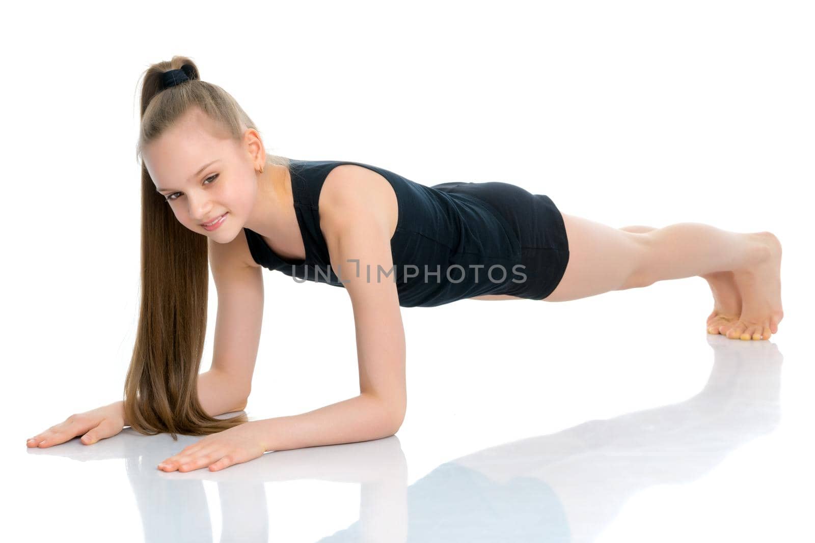 A girl gymnast performs an acrobatic element on the floor. The concept of childhood, sport, healthy lifestyle. Isolated on white background.