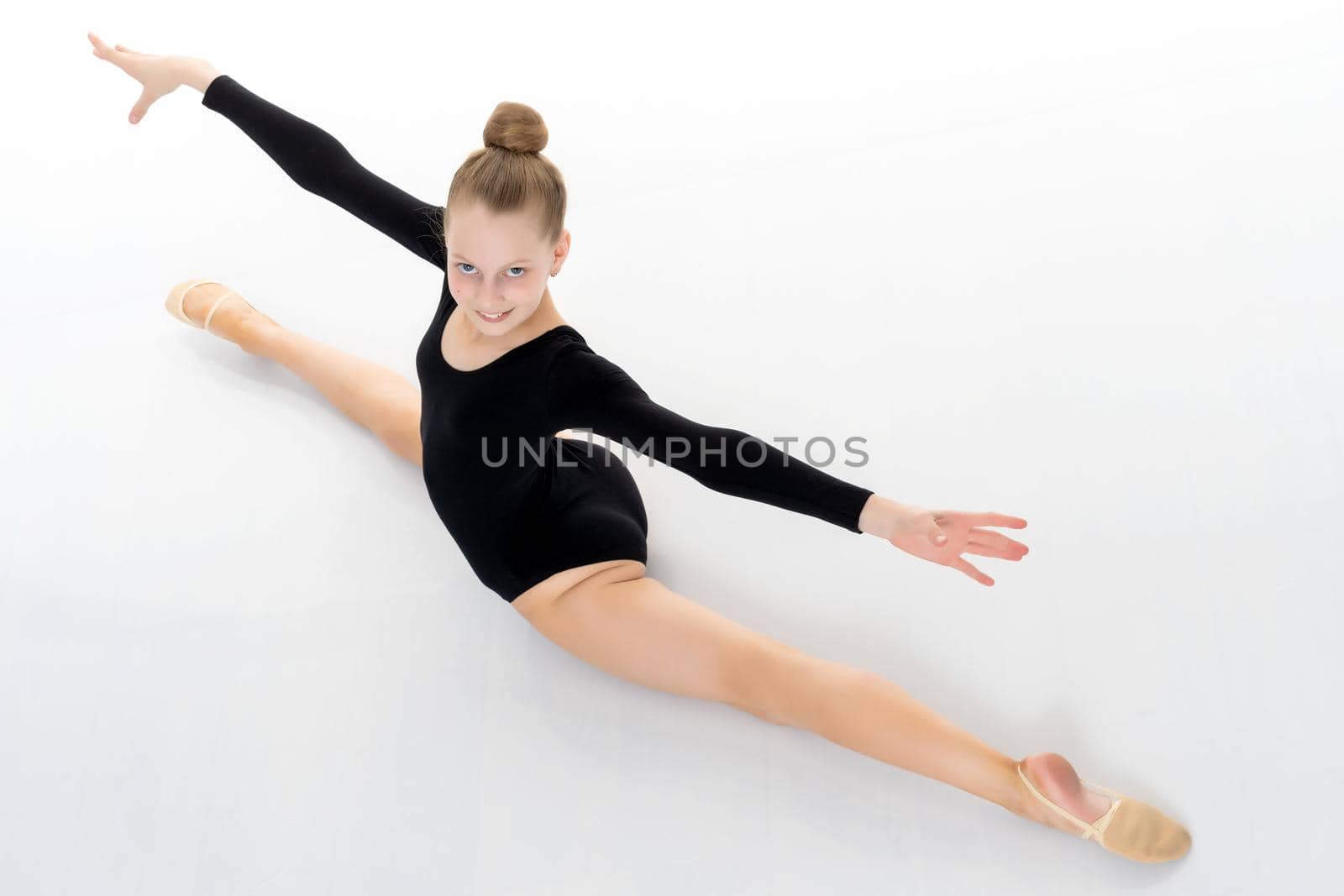 A little girl performs a gymnastic twine. The concept of fitness and sports. Isolated on white background.