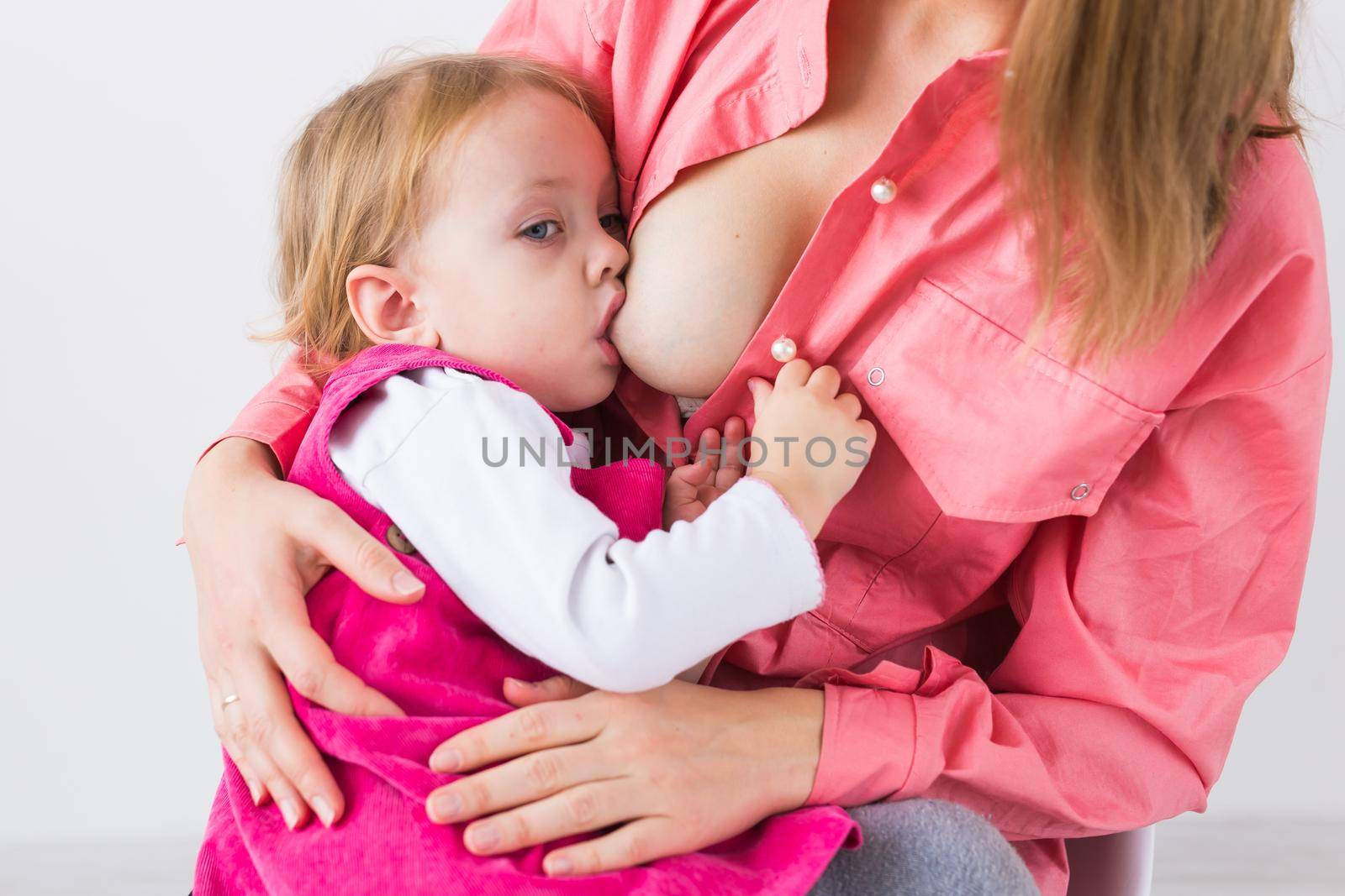 Motherhood and family concept - mother breast feeding and hugging her baby, close-up. by Satura86