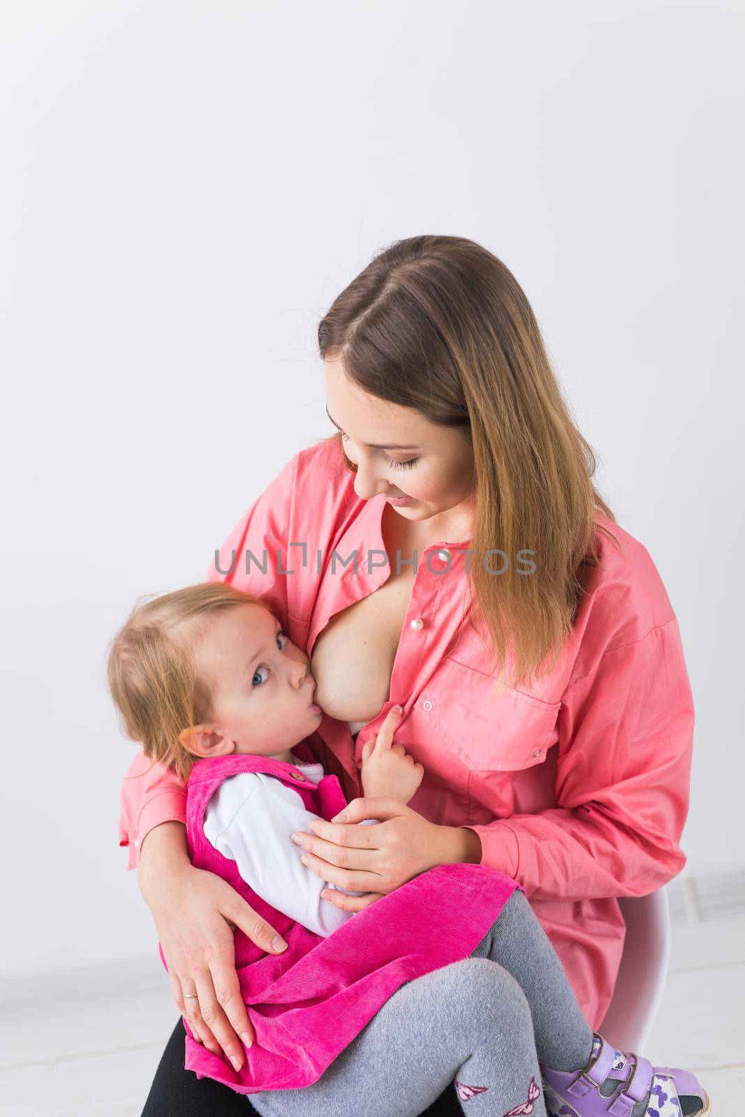 Young beautiful mother, breastfeeding her baby girl. Mom breastfeeding infant.