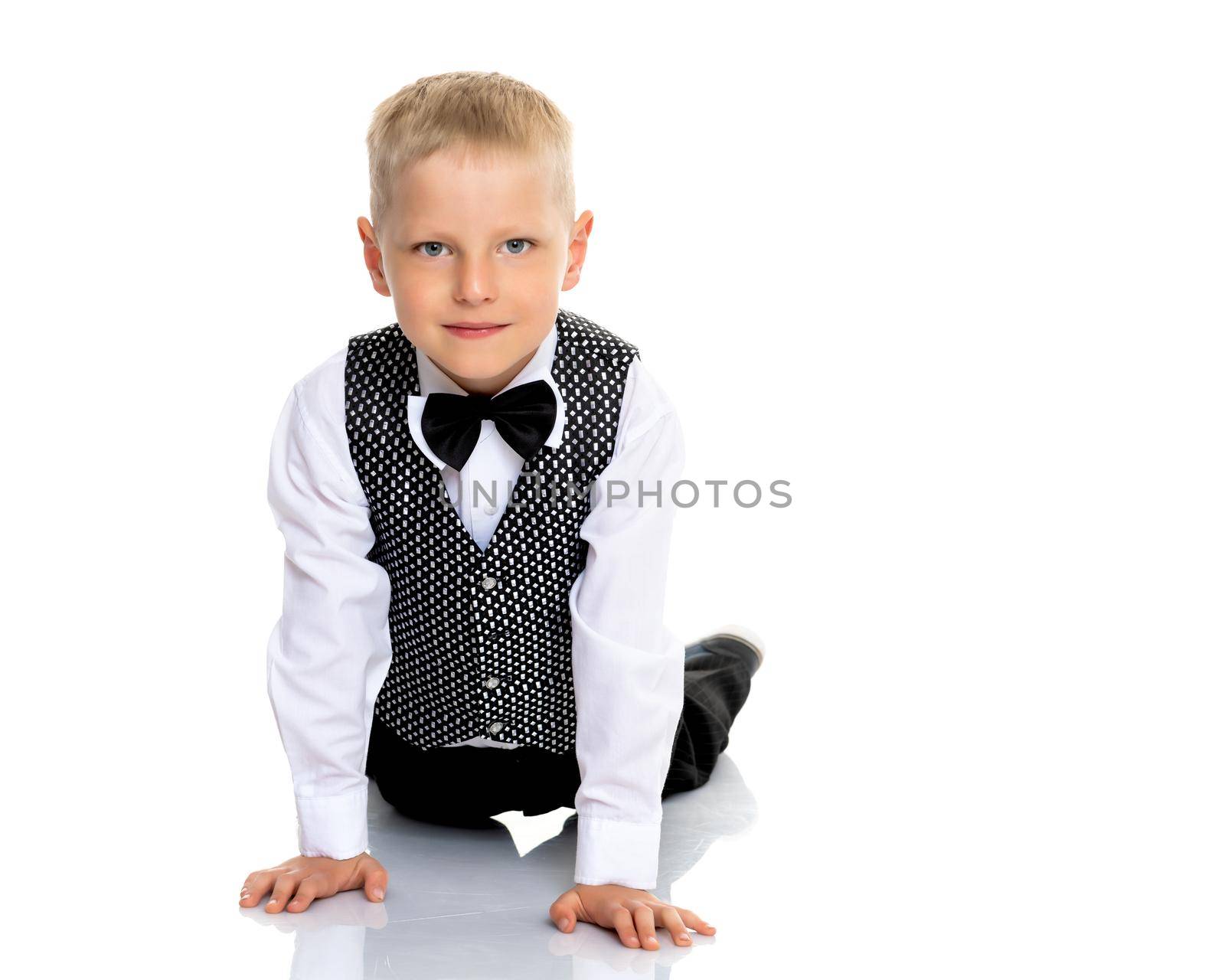 Happy little boy lies on the floor in the studio on a white background. The concept of a happy childhood, rest and vacation. Isolated.