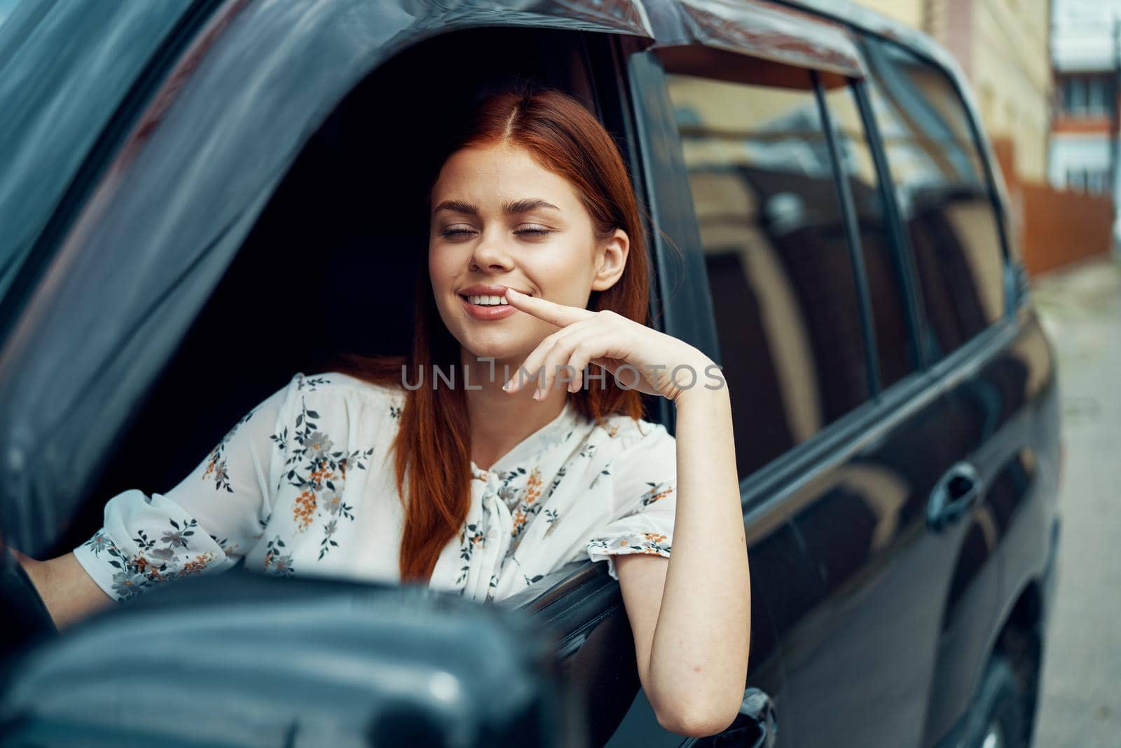 cheerful woman driving a car looks out of the window. High quality photo