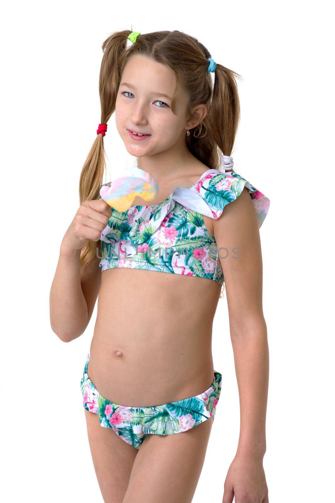 Beautiful girl in a swimsuit, with ice cream in her hand. Beautiful little girl of ten years old with pigtails posing in the studio on a white background. Happy girl having summer vacation