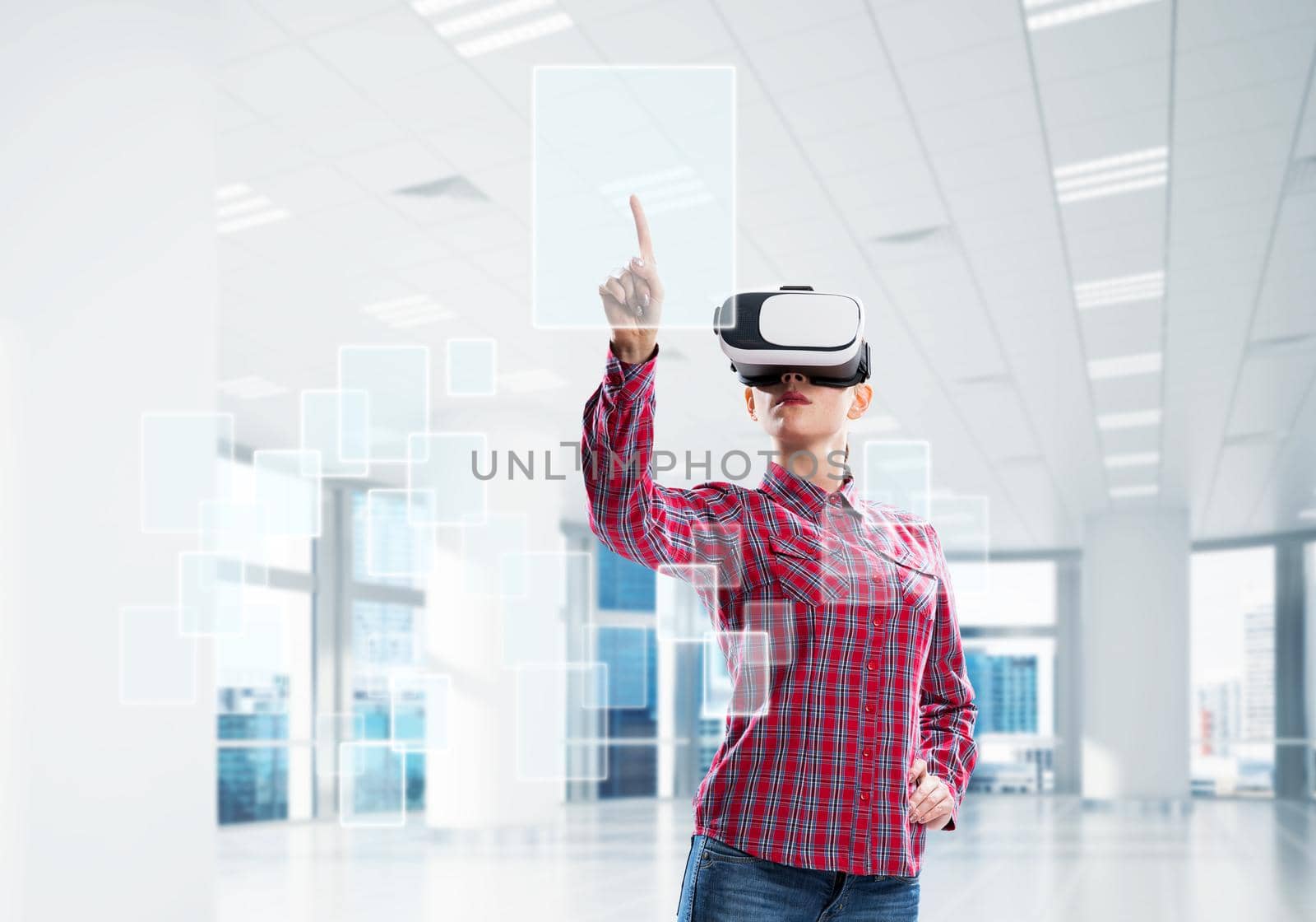 Woman in casual wearing virtual reality mask and touching icon on screen. Mixed media