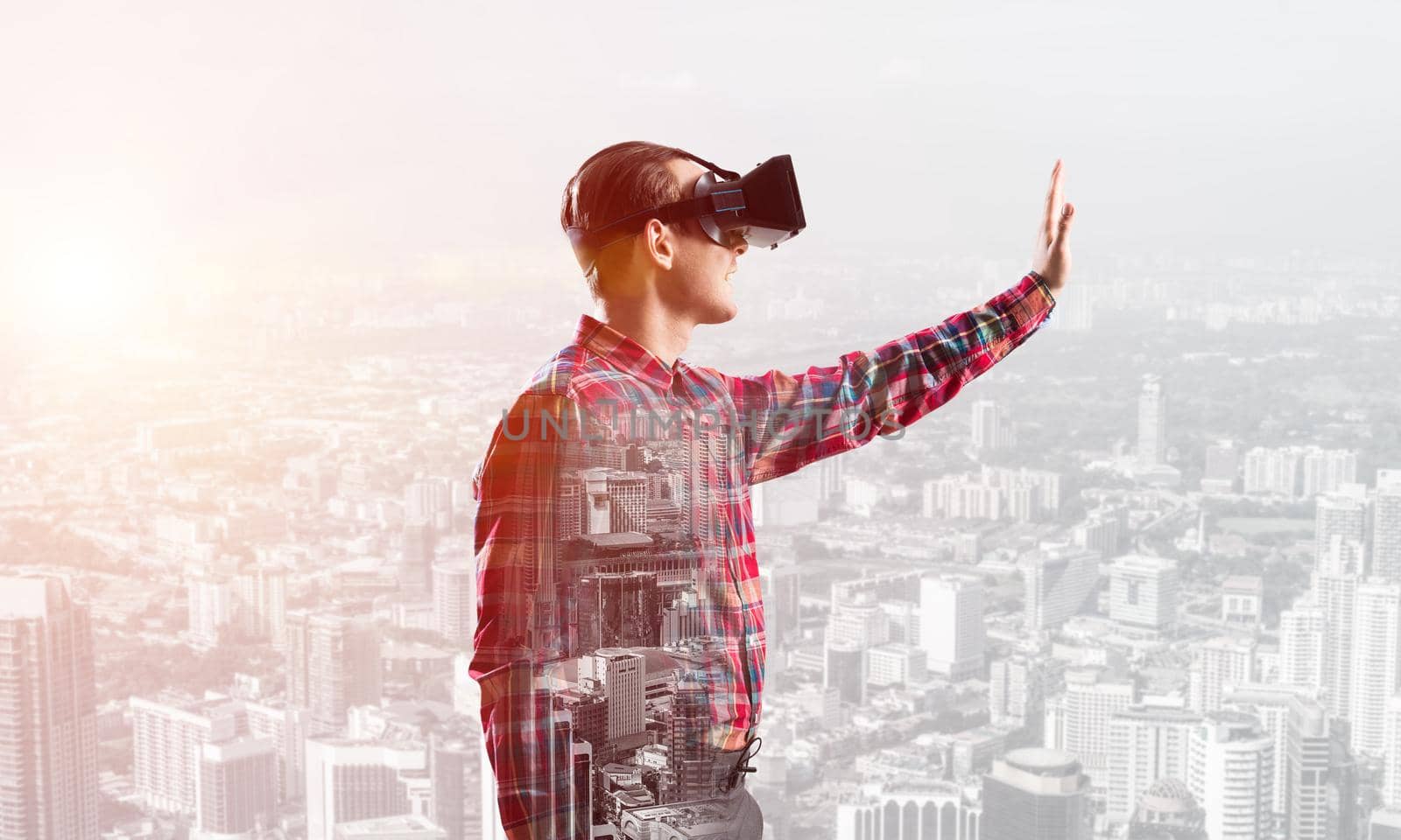 Young man with virtual reality headset or 3d glasses over cityscape background