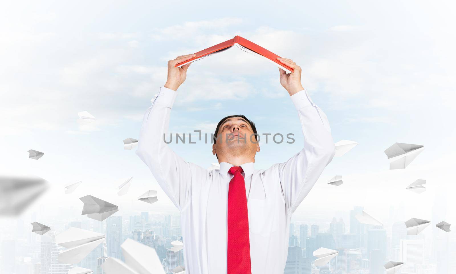 Senior businessman holding open diary overhead. Man in shirt and tie standing on cityscape background with flying paper planes. Education and professional knowledges. Time management and planning