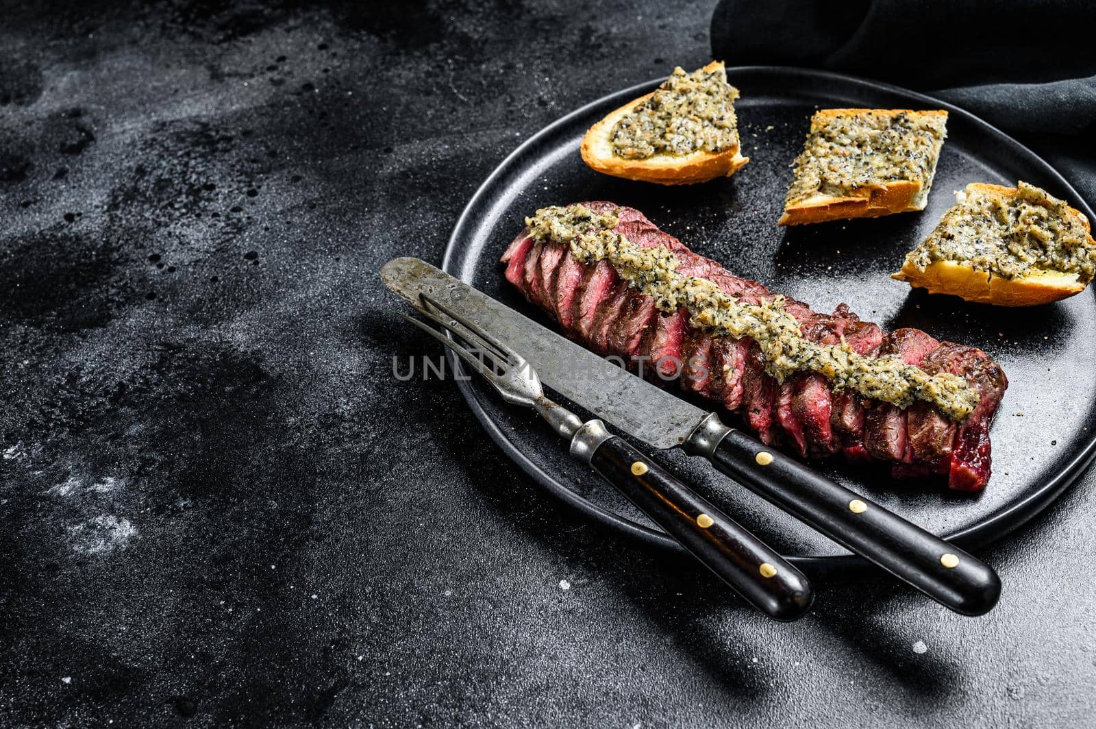 Grilled skirt or machete marble beef steak. Black background. Top view. Copy space.