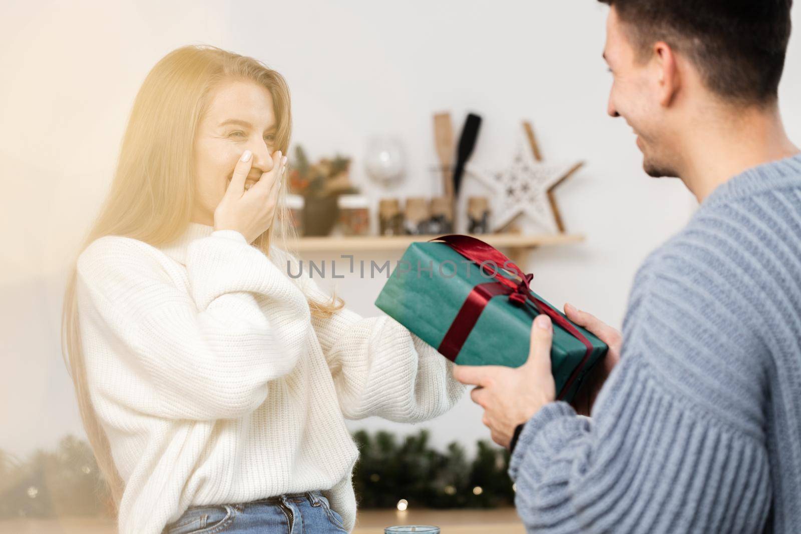 Sweet young couple opening Christmas gifts in the living room at home
